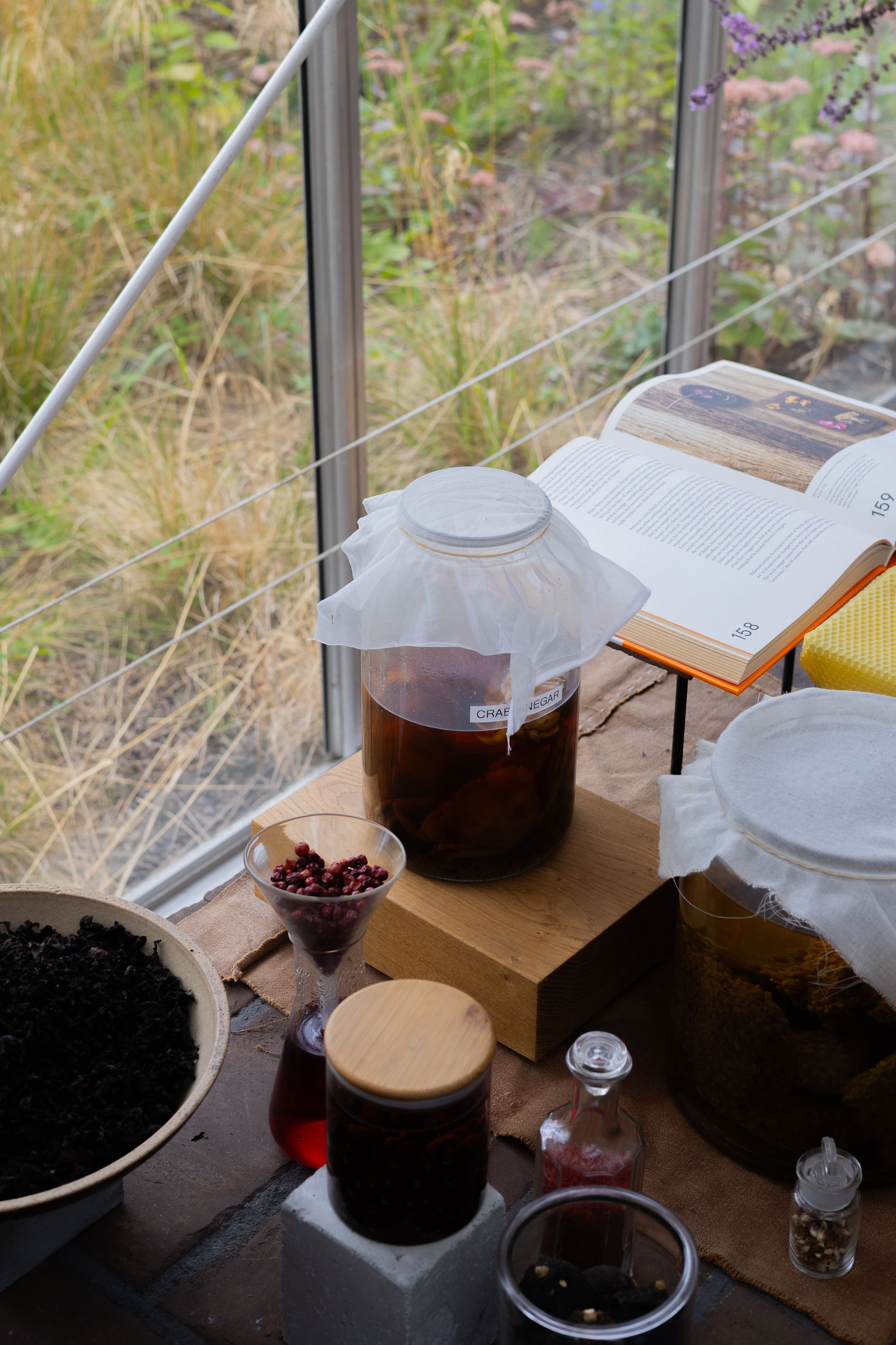 A wine-making process shown in progress with multiple glass containers and fermentation vessels on a windowsill.