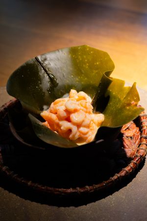 Fresh shrimp served on a dark plate with a green leaf garnish in dramatic lighting.