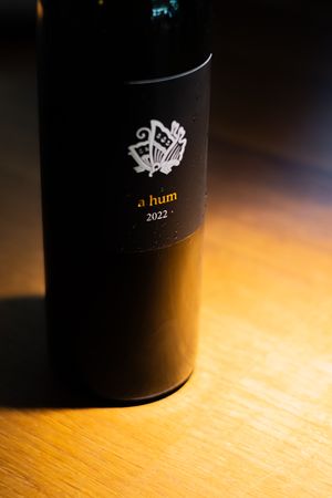 Black cylindrical container with minimalist design illuminated by warm light on wooden surface.