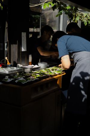 Kitchen staff plating dishes in a dimly lit restaurant setting.
