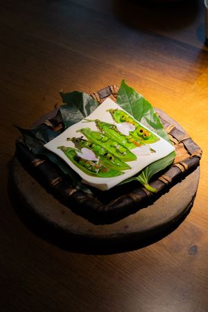 Fresh green vegetables artfully presented on a rustic dark plate.