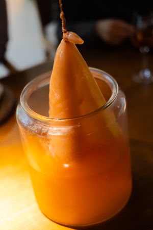 Vibrant orange smoothie or juice drink served in a clear glass with artistic presentation.