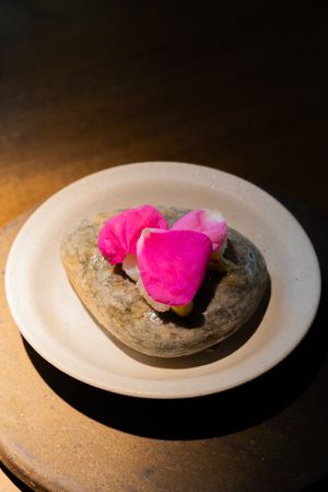 Vibrant pink garnish artistically placed on a white ceramic plate with dark accents.