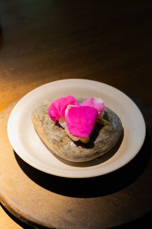 Bright pink garnish presented on a stone-like surface against white ceramic plate.