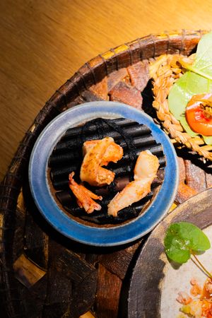 A sequence of plated salmon pieces with garnish on blue ceramic plates against a wooden surface.