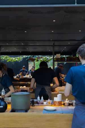 Modern restaurant interior with diners seated at tables near large windows.