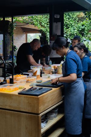 Kitchen staff preparing food at a wooden prep station in a restaurant kitchen.