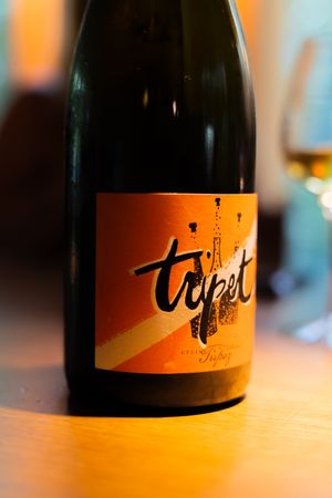 Several dark wine bottles with orange labels displayed in warm lighting.