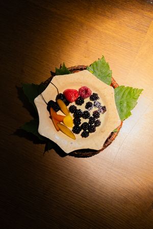 Fresh berries served on wax paper with green garnish in dramatic spotlight.