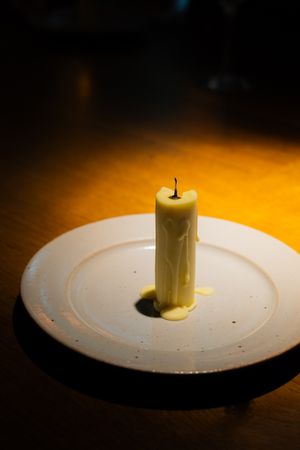 Cylindrical white food item dramatically presented on white plate with spotlighting.