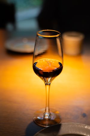 Wine glass with amber-colored liquid photographed against warm backlight.