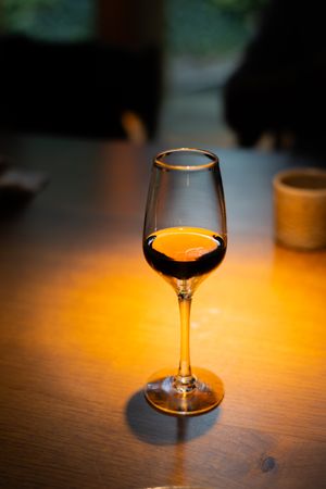 Series of elegant cognac glasses with amber liquid illuminated by warm ambient lighting on wooden surface.