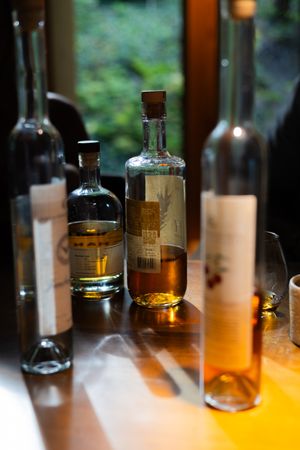 Collection of amber liquor bottles displayed with backlighting on wooden surface.