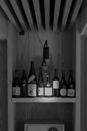 Collection of wine bottles displayed on a wooden shelf against a dark wall.