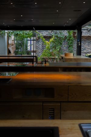 Modern restaurant interior with wooden bar and brick walls illuminated by natural light.