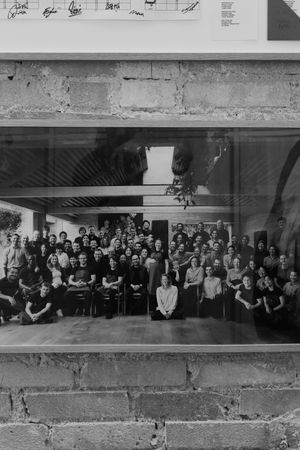 Large black and white panoramic group photograph in an indoor setting.