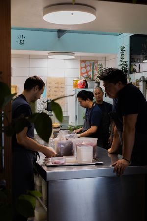 Several workers in a commercial kitchen preparing food together under modern lighting fixtures.