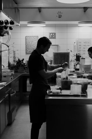 Silhouette of a restaurant worker preparing food in a dimly lit commercial kitchen.