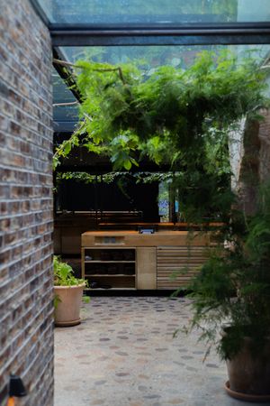Outdoor patio space with brick walls and wooden benches surrounded by lush greenery.