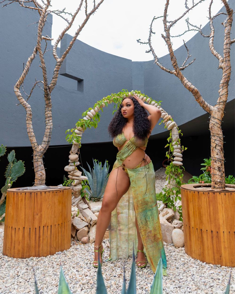 A series of five similar photos showing someone in a green dress posing against a wooden fence with mountains in the background.