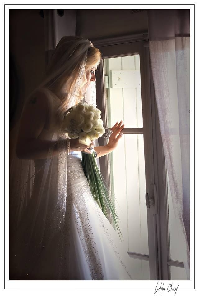 Bride holding her bouquet while looking out the window at Château de Pouget, South of France destination wedding captured in fine art style