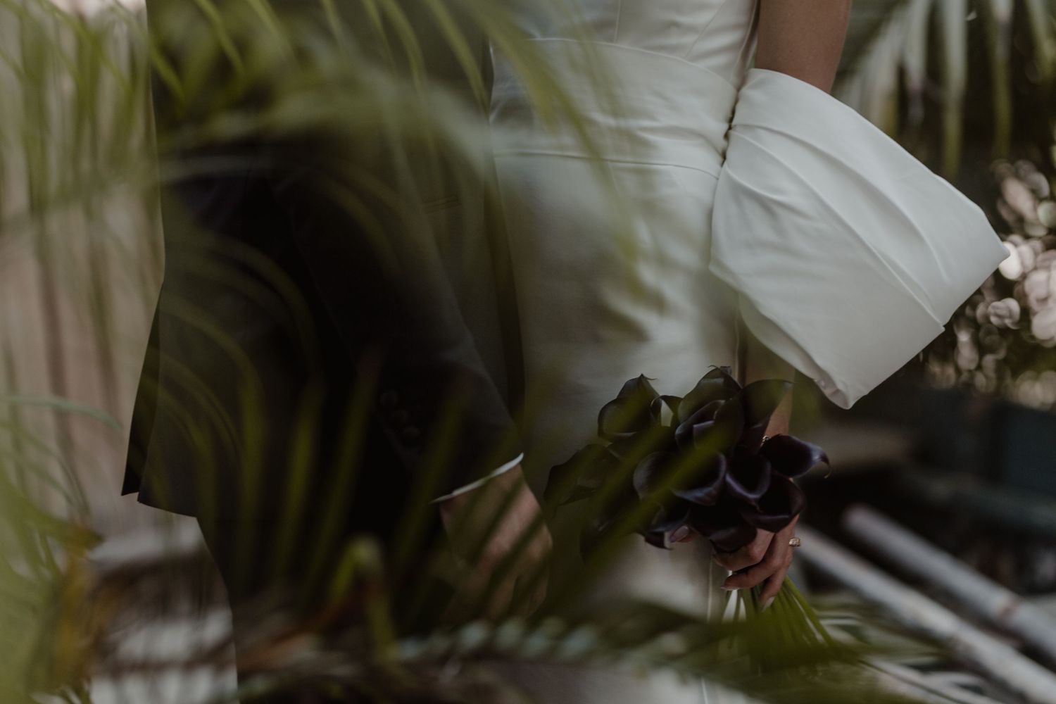 A couple shares an intimate moment under a canopy of magnolia trees in bloom during a spring wedding.