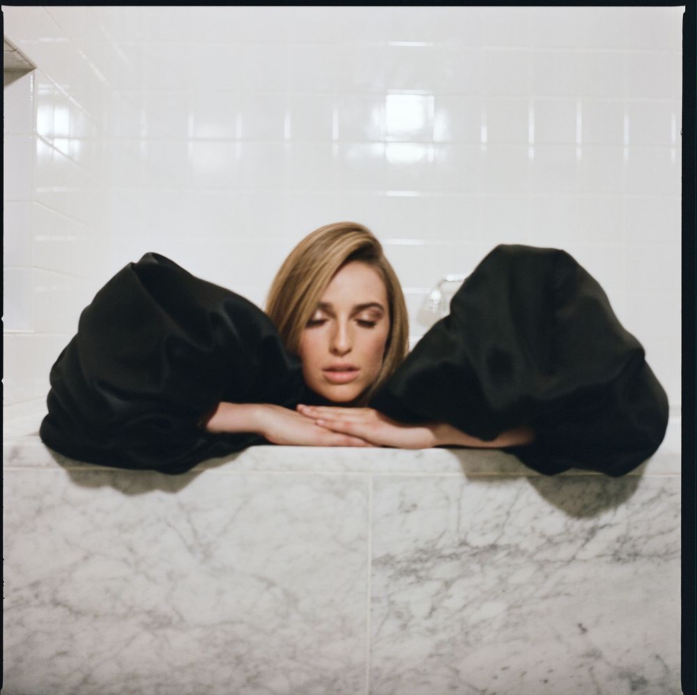 Series of artistic black and white photographs showing a figure gradually emerging from a black surface.