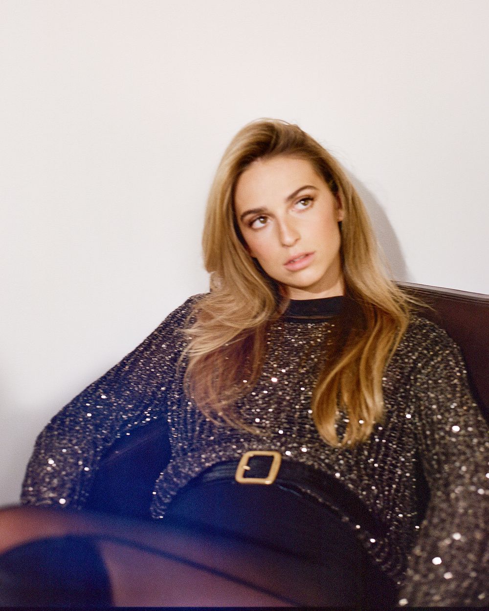 A sequence of photos showing a woman in a dark sparkly dress posing on a dark blue background.