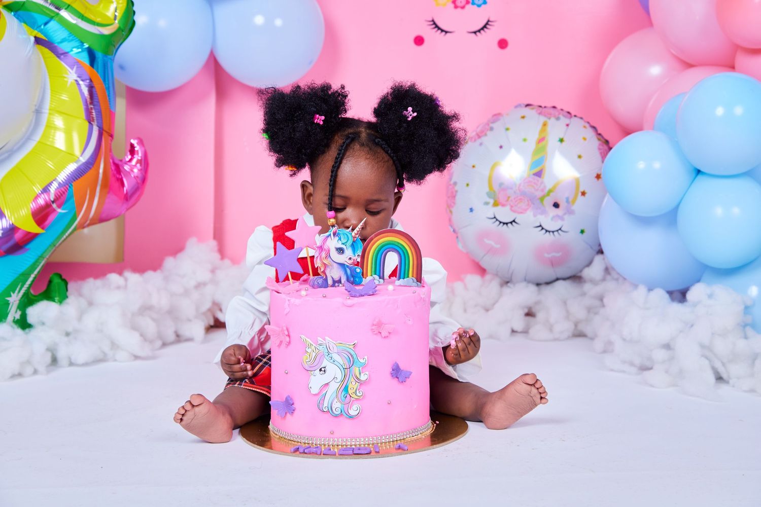 Birthday celebration scene with pink unicorn cake and colorful balloon decorations.