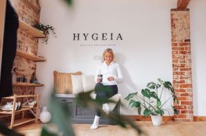 Interior space of Hygeia wellness studio with exposed brick walls, wooden shelves, plants and white seating area.