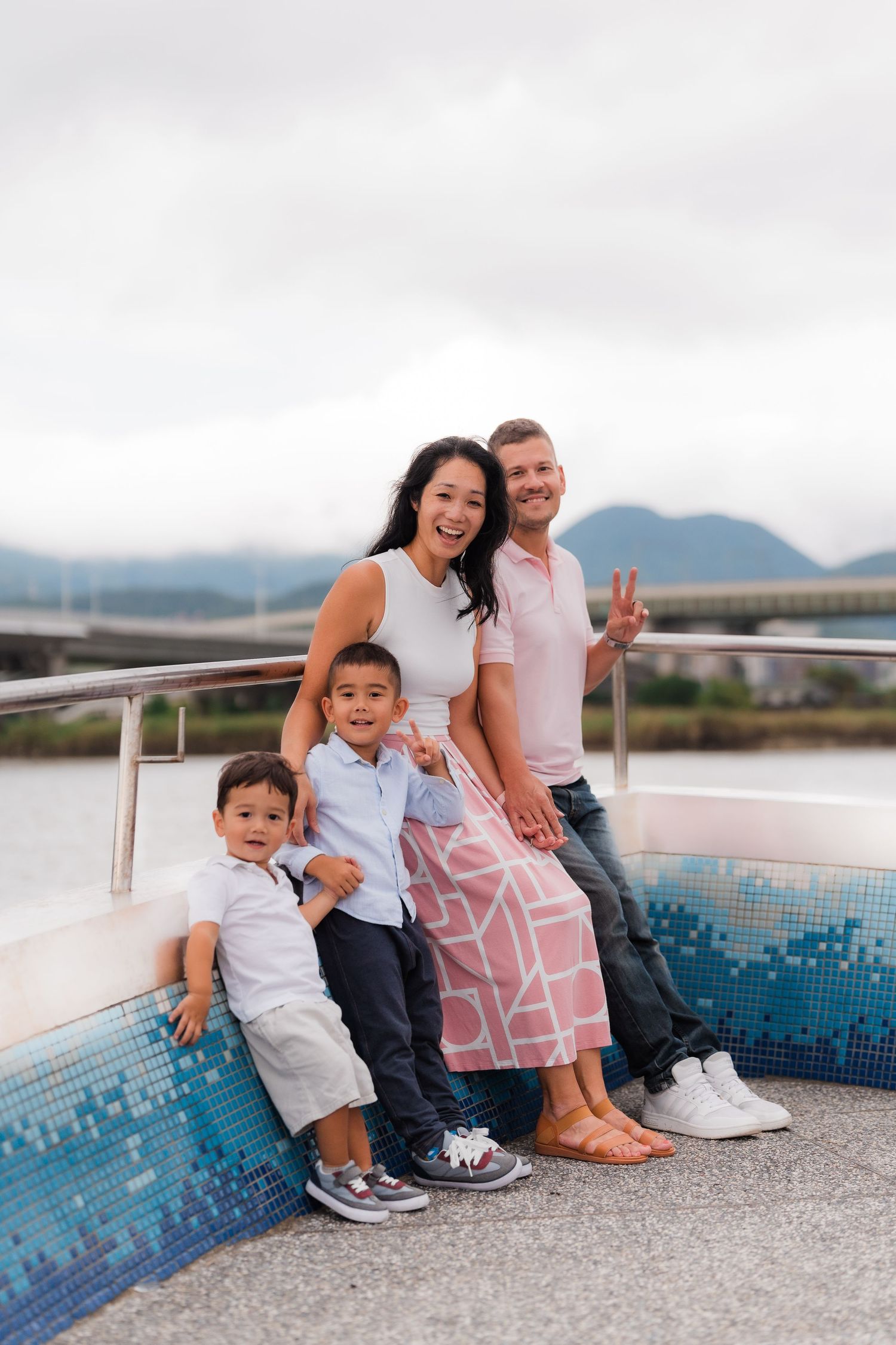 A happy family posing together against a mountainous backdrop near a mosaic wall.
