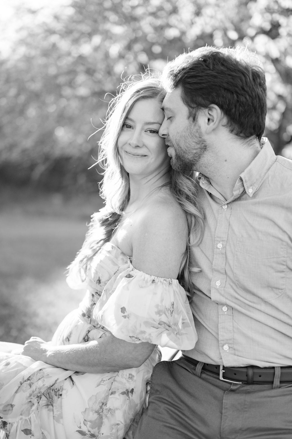 A tender romantic moment captured in black and white during golden hour.