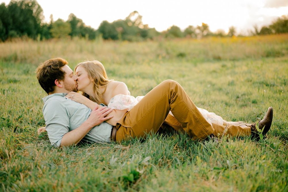 Two people sharing an intimate moment while lying in a grassy meadow.