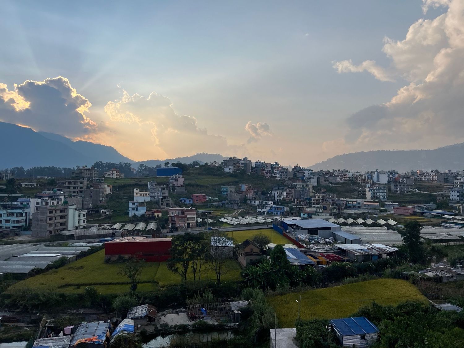 Panoramic cityscape view with mountains and buildings during sunset.