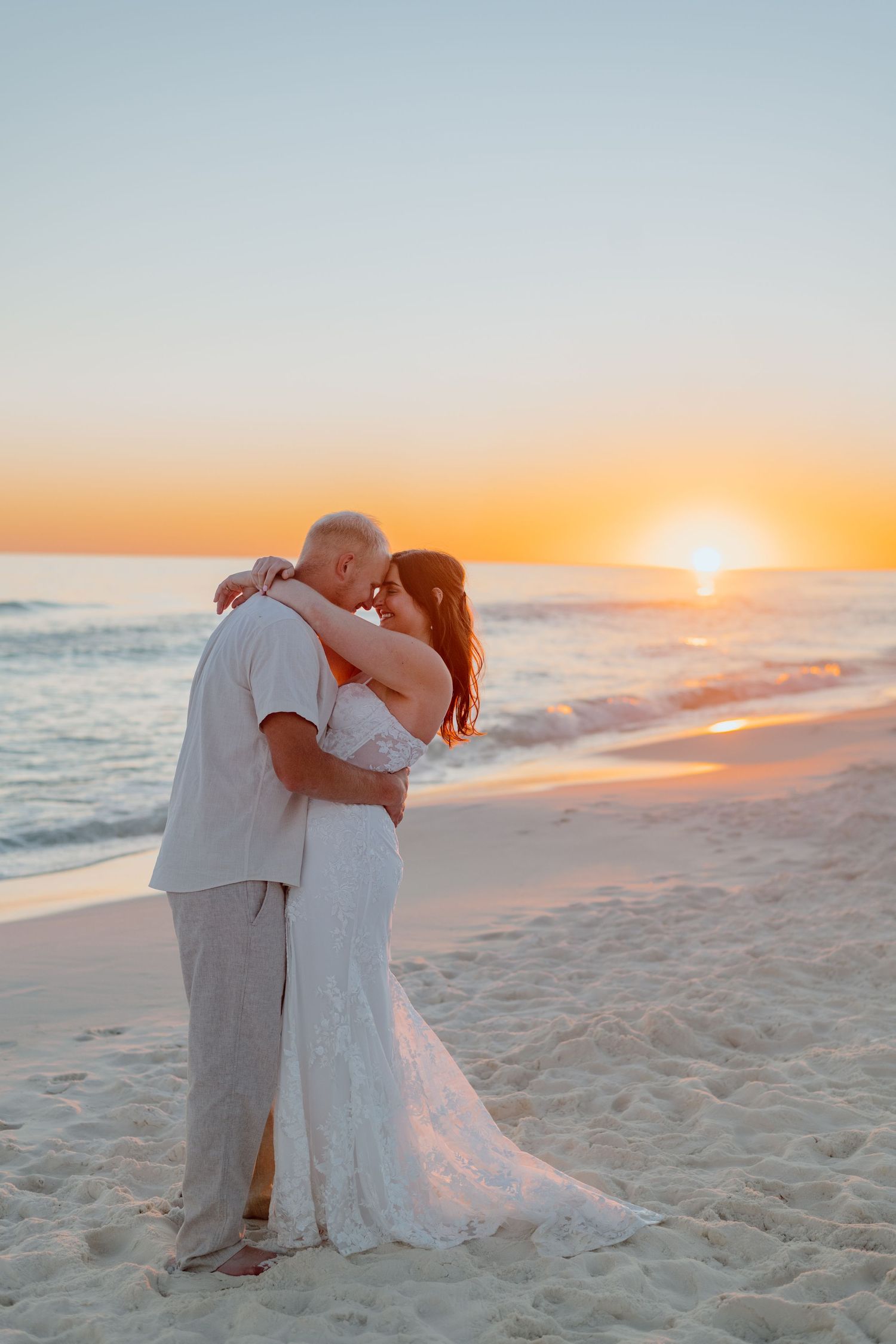 Black and white portrait of couple embracing on beach at sunset.