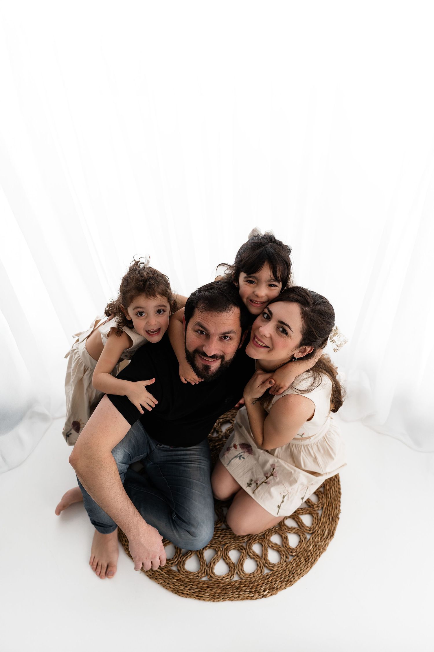 Three artistic family photos showing parents and children cuddling together on a woven rattan surface with white backdrop.