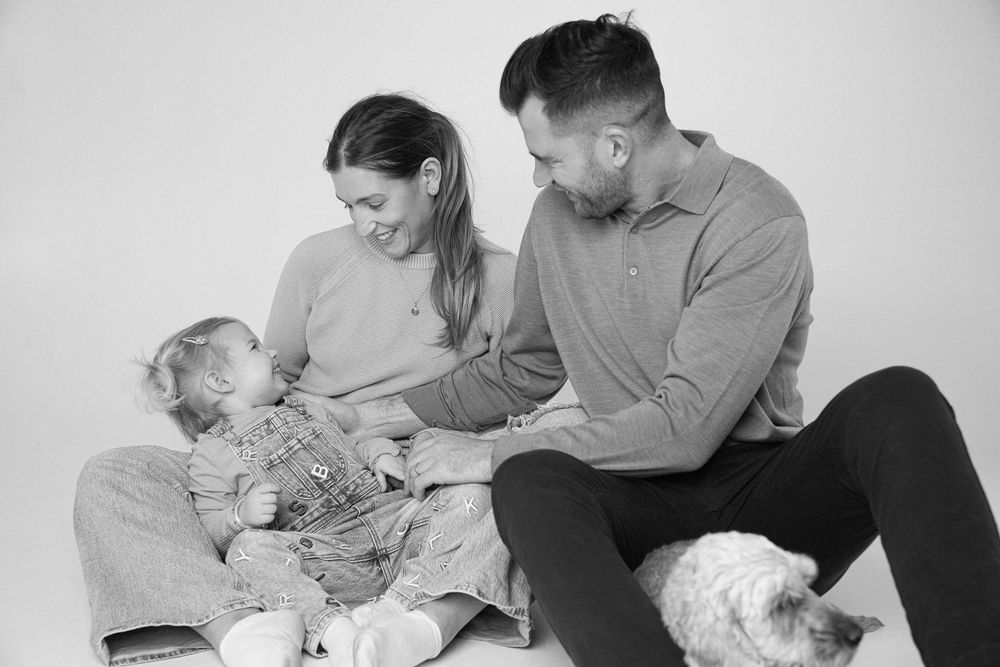 Black and white photo series showing tender family moments with a newborn baby and parents at home.