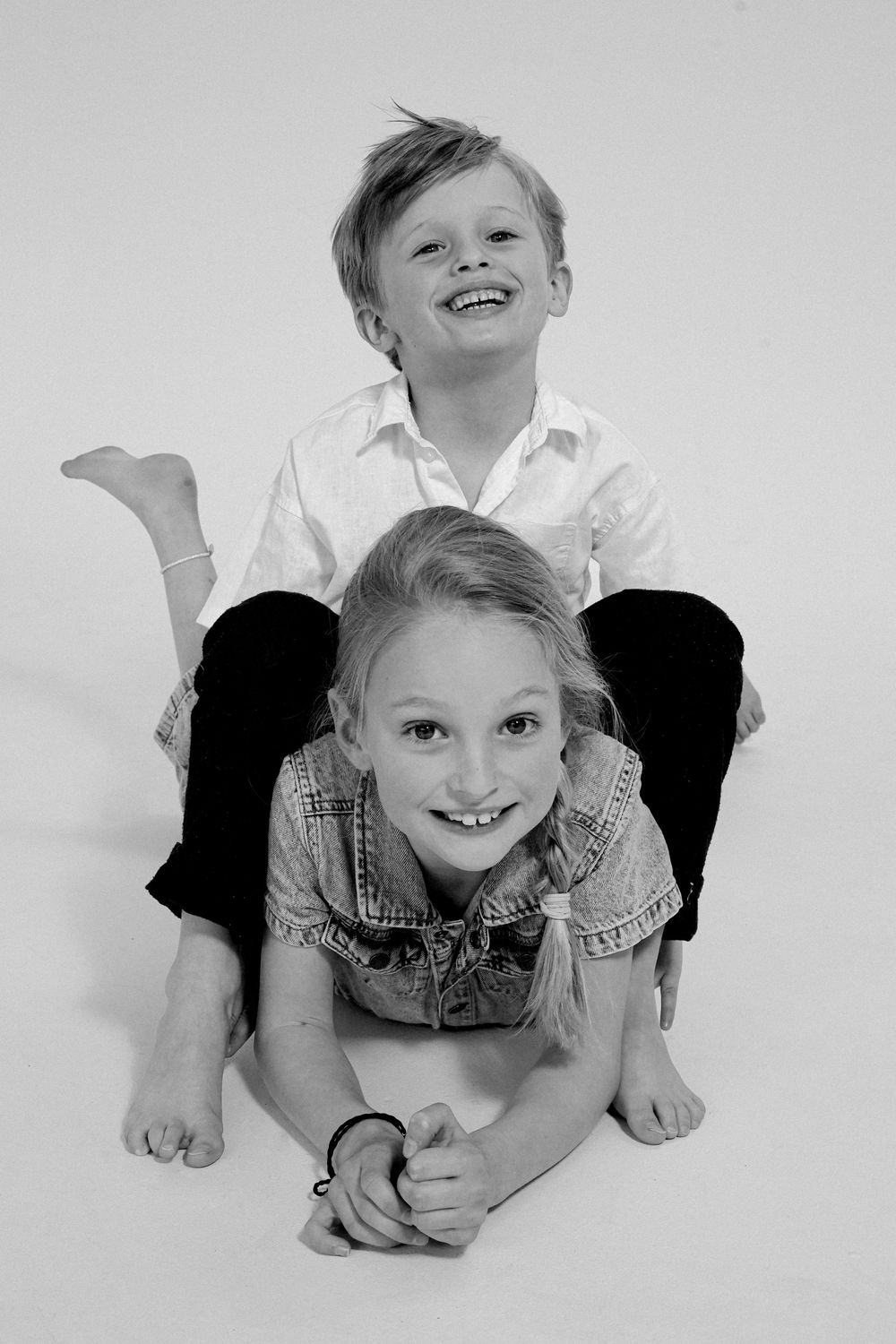 Two children playfully posing together in black and white studio photograph