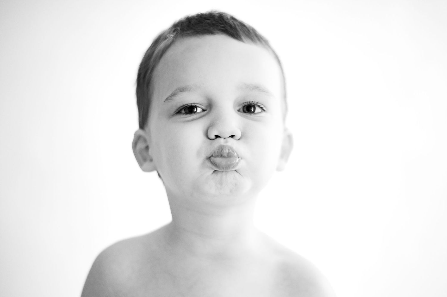 Three black and white studio portraits of a young child with expressive poses and subtle lighting.