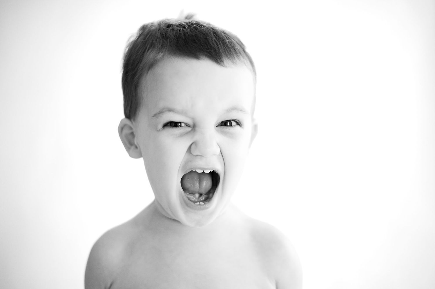A black and white portrait shows an energetic child with mouth wide open in playful expression.