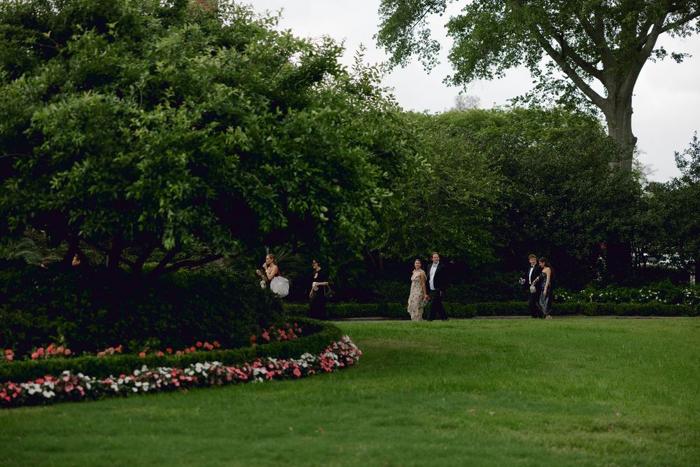 People enjoy a summer day in a peaceful garden with lush green grass and colorful flower beds.