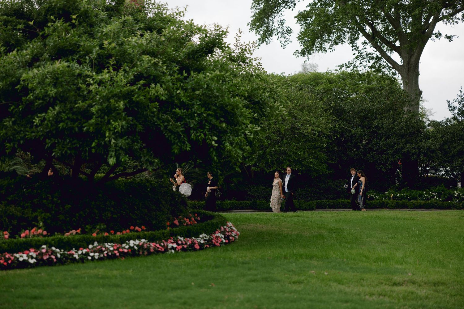 People enjoy a summer day in a peaceful garden with lush green grass and colorful flower beds.