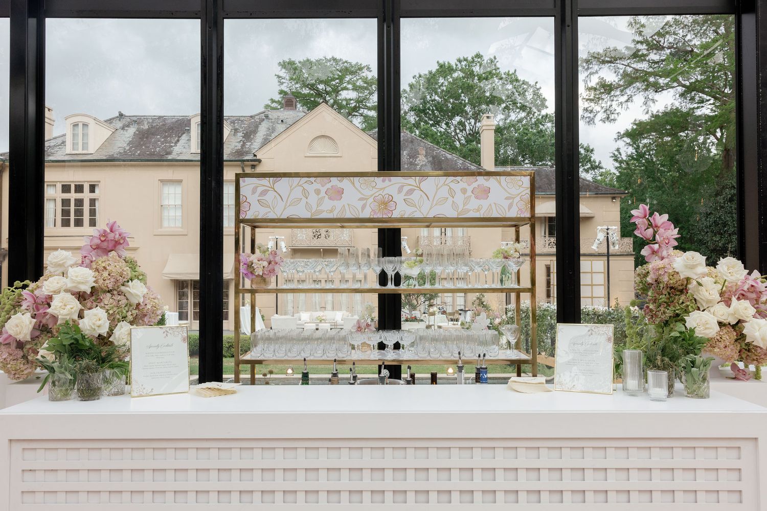 An elegant wedding bar display with rose floral arrangements and windows overlooking buildings in the background.