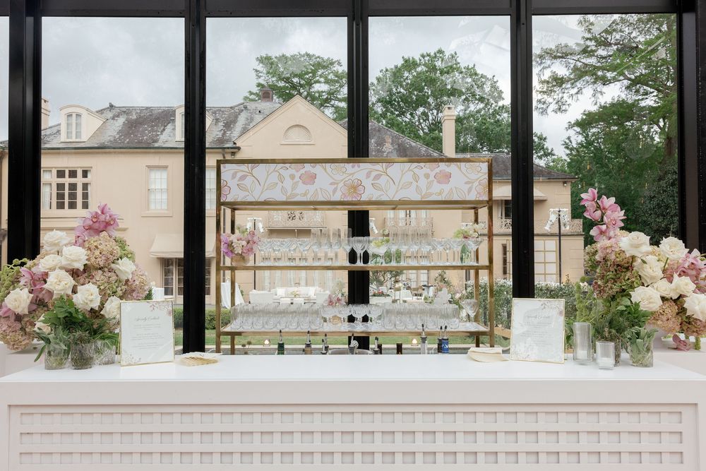 An elegant wedding bar display with rose floral arrangements and windows overlooking buildings in the background.
