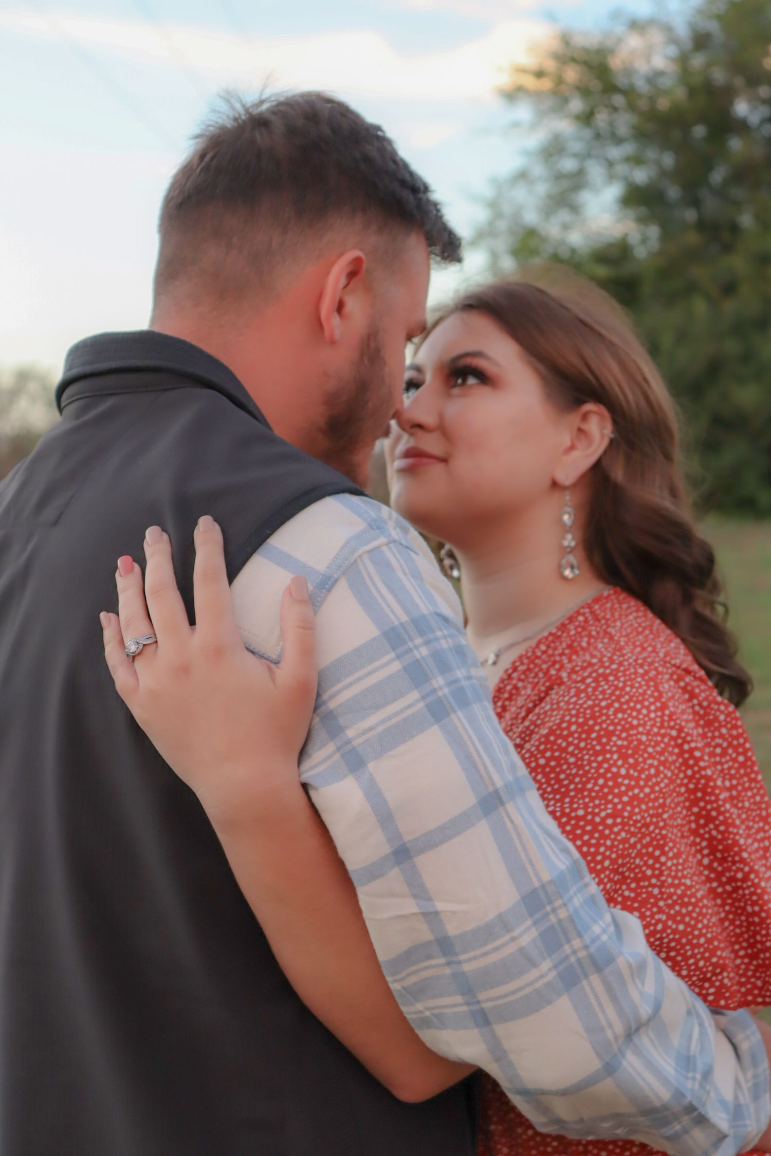 Romantic engagement photo series with couple in blue plaid and red dress outdoors.