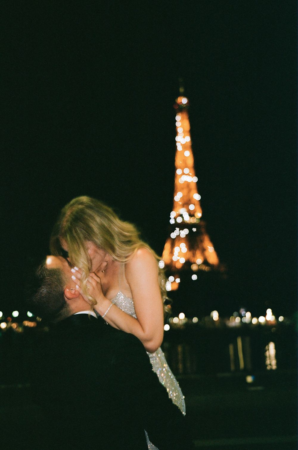 Romantic nighttime scene in Paris with glowing Eiffel Tower illuminated in orange against dark sky. best paris evening photoshoot