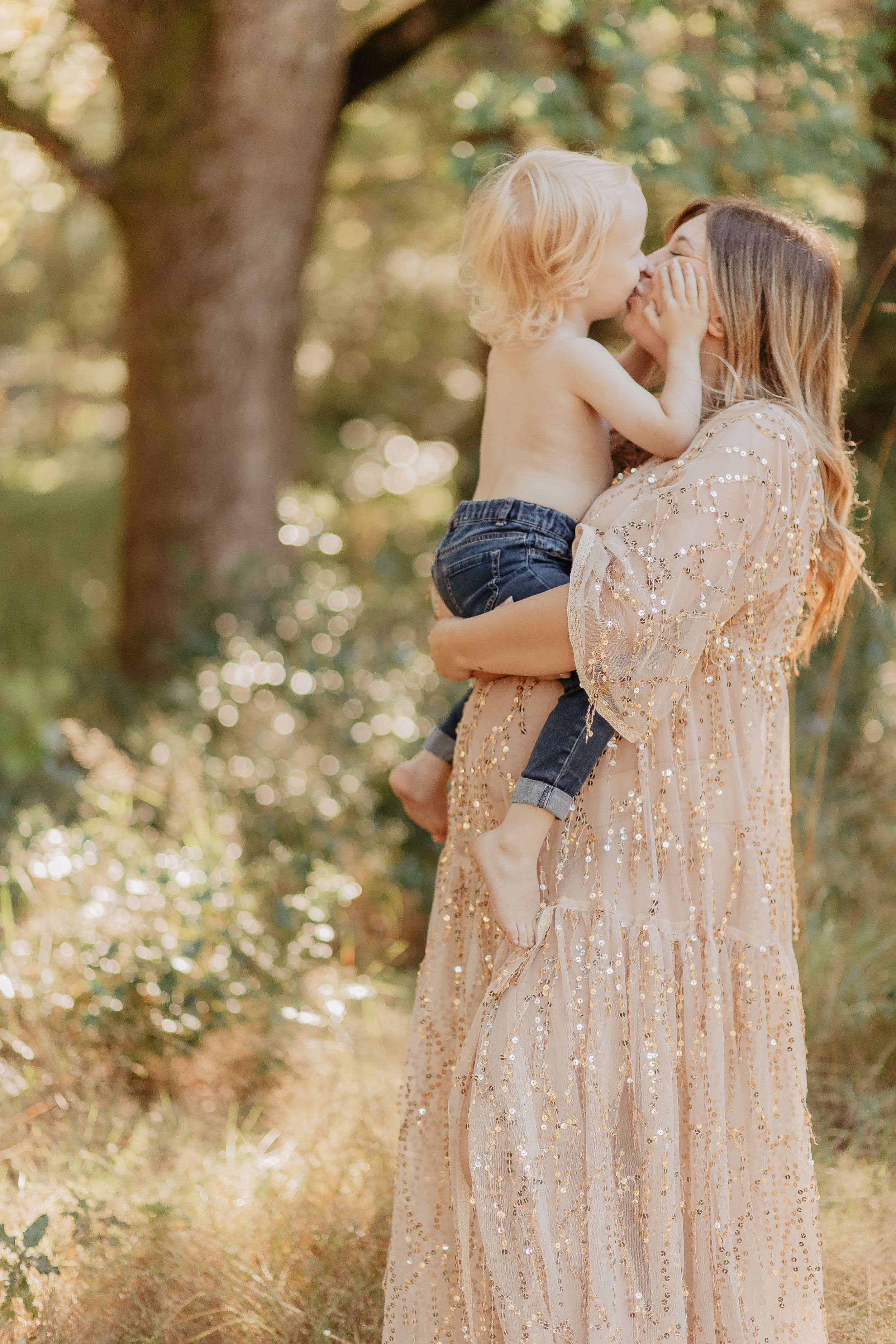 Mother and child sharing tender moments in a sunlit forest wearing matching lace dresses.
