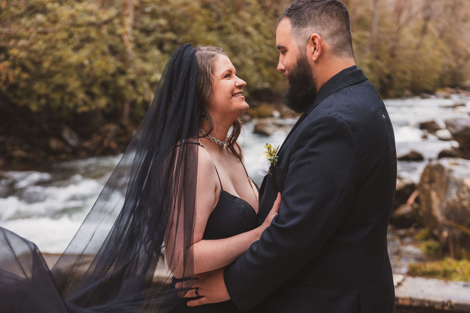 A couple shares intimate moments outdoors during a winter photo session along a snowy riverbank.