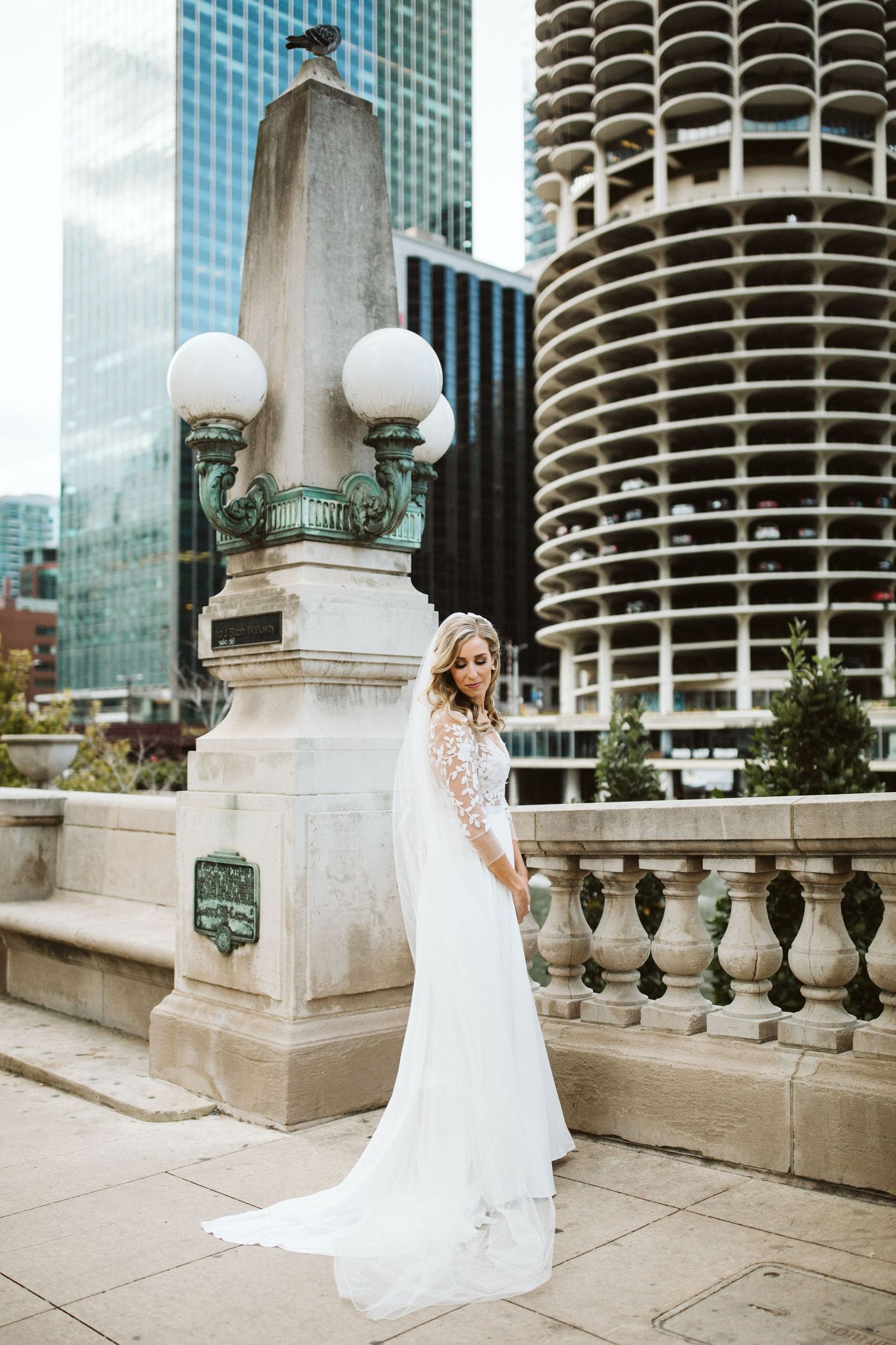 Bride in flowing white dress poses against iconic Marina City towers in Chicago.