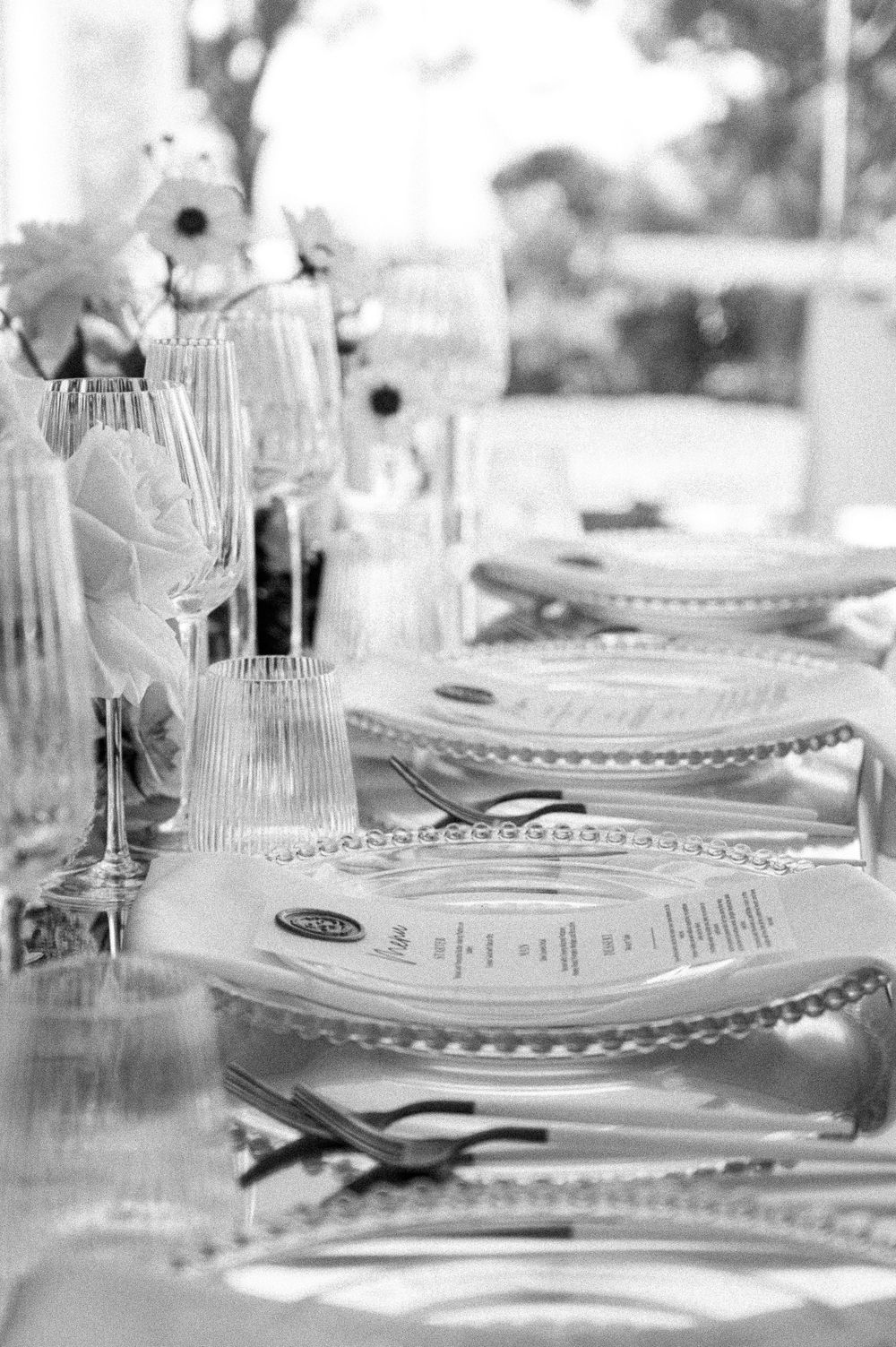 An elegant black and white table setting with ornate plates, silverware and wine glasses for a formal dinner party.